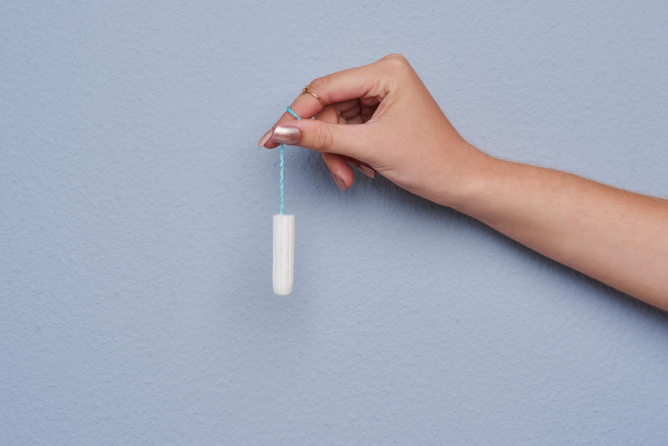 Cropped studio shot of a woman's hand holding a tampon against grey background