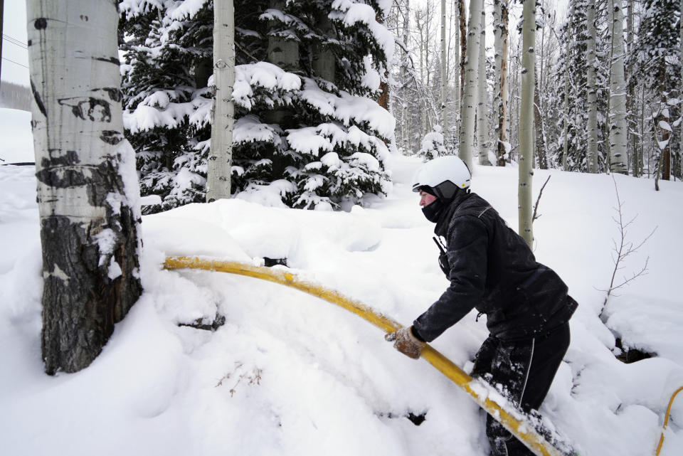 Ian Sidwell adjusts a hose at Vail Mountain Resort, Wednesday, Dec. 29, 2021, in Vail, Colo. Newer snowmaking technology is allowing ski areas to be more efficient with energy and water usage as climate change continues to threaten snowpack levels. (AP Photo/Brittany Peterson)