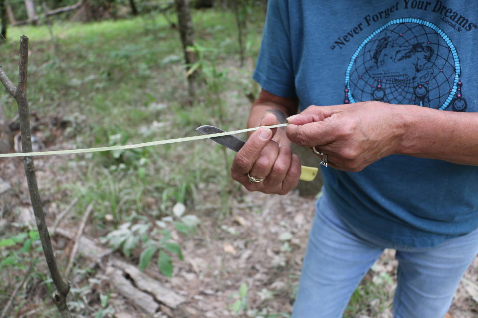 Rose Fisher Greer demonstrates how she shaves down the river cane using her knife to prepare it for use in weaving.