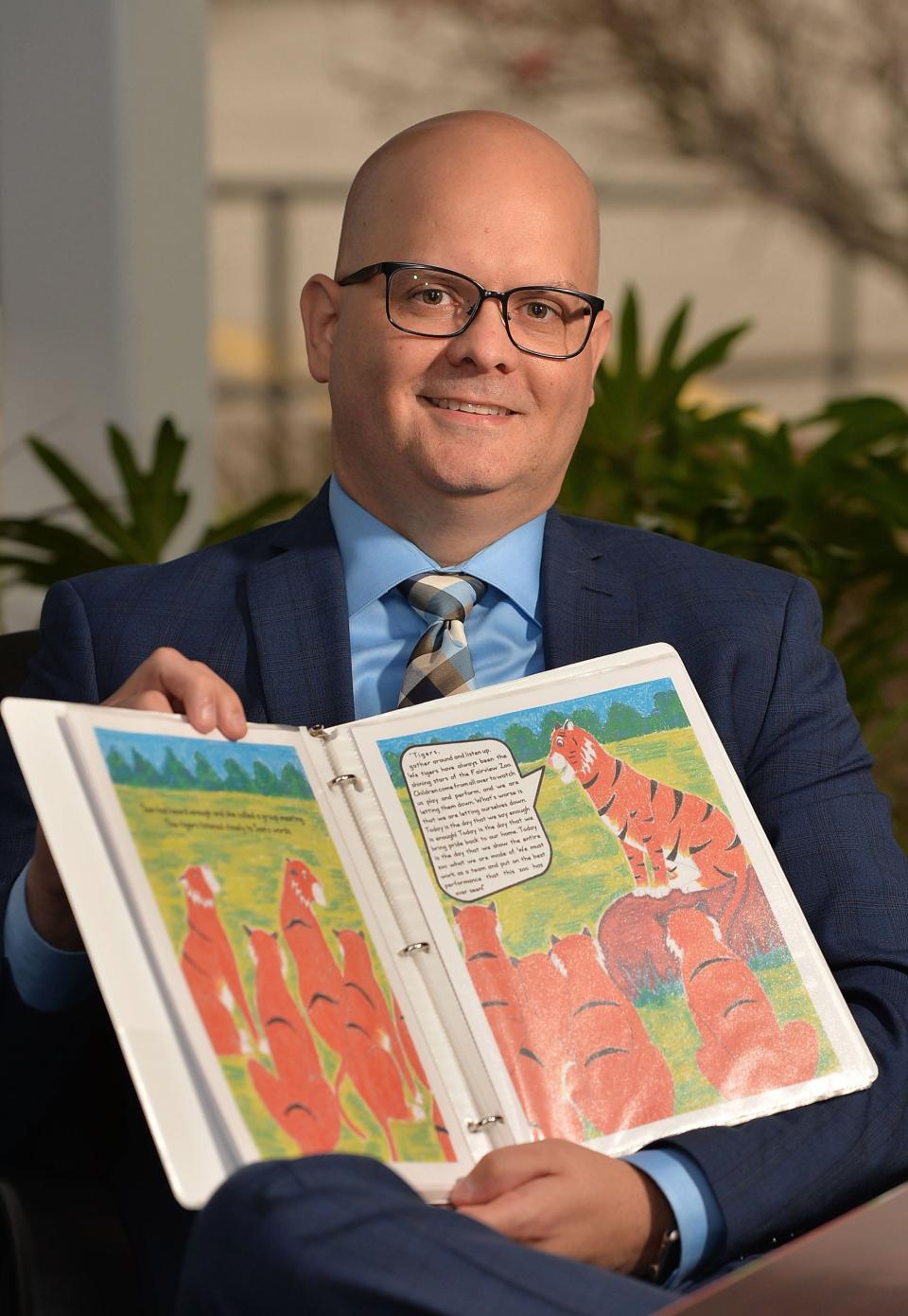 In November 2018, Erik Kincade, superintendent of the Fairview School District, displays a mock-up of his book "Earn Your Stripes" which features a female tiger, which is the Fairview School District mascot.