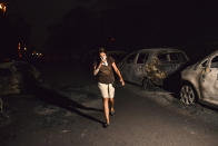 <p>A woman walks in front of burnt cars at the village of Mati during a wildfire near Athens, on July 23, 2018. (Photo: Angelos Tzortzinis/AFP/Getty Images) </p>