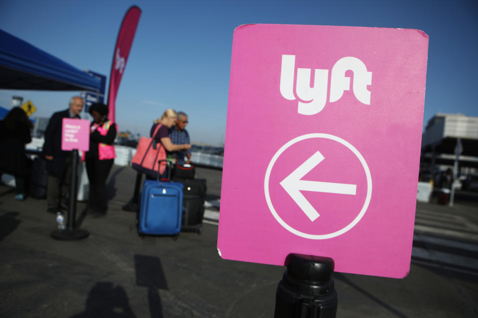 LOS ANGELES, CALIFORNIA - NOVEMBER 06: Arriving passengers wait to board Lyft vehicles at the new 'LAX-it' ride-hail passenger pickup lot at Los Angeles International Airport (LAX) on November 6, 2019 in Los Angeles, California. The airport has instituted a ban on Lyft, Uber and taxi curbside pickups as airport construction increases during a modernization program. Passengers have complained of long wait times and confusion at the pickup area, especially during peak hours. Passengers must depart their terminal and then ride a shuttle bus or walk to the separate pickup lot.  (Photo by Mario Tama/Getty Images)
