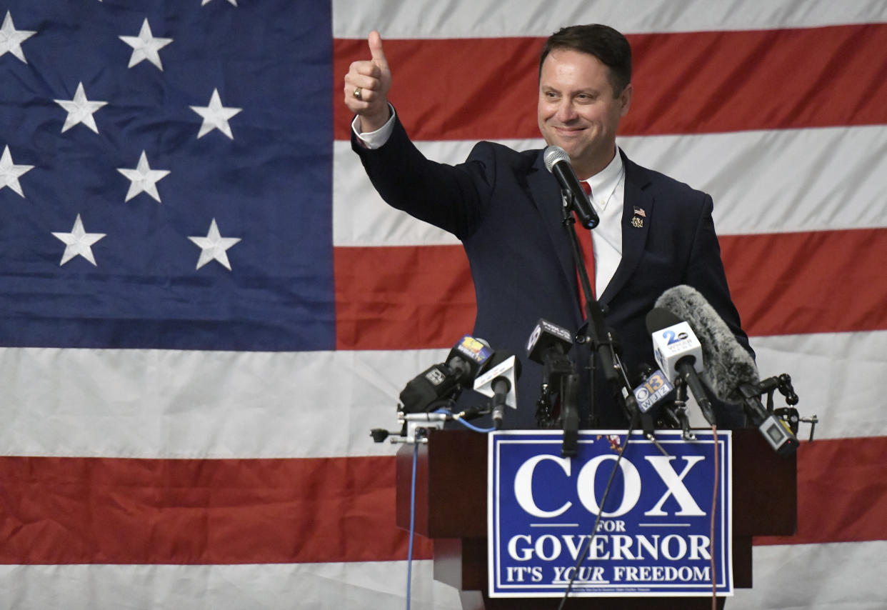 Dan Cox gives the thumbs-up at a podium that says: Cox for Governor, It's Your Freedom.