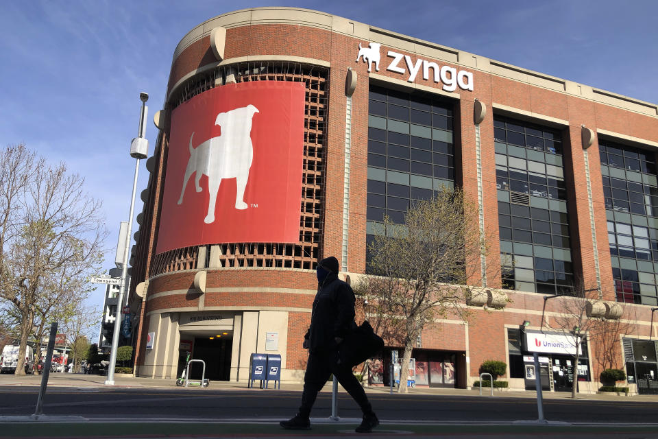 FILE - A pedestrian walks in front of a sign at Zynga in San Francisco, Tuesday, March 16, 2021. Take-Two Interactive, maker of Grand Theft Auto and Red Dead Redemption, is buying Zynga, maker of FarmVille and Words With Friends, in a cash-and-stock deal with an enterprise value of about $12.7 billion. Take-Two said Monday, Jan. 10, 2022, it anticipates $100 million in annual cost savings. (AP Photo/Jeff Chiu, File)