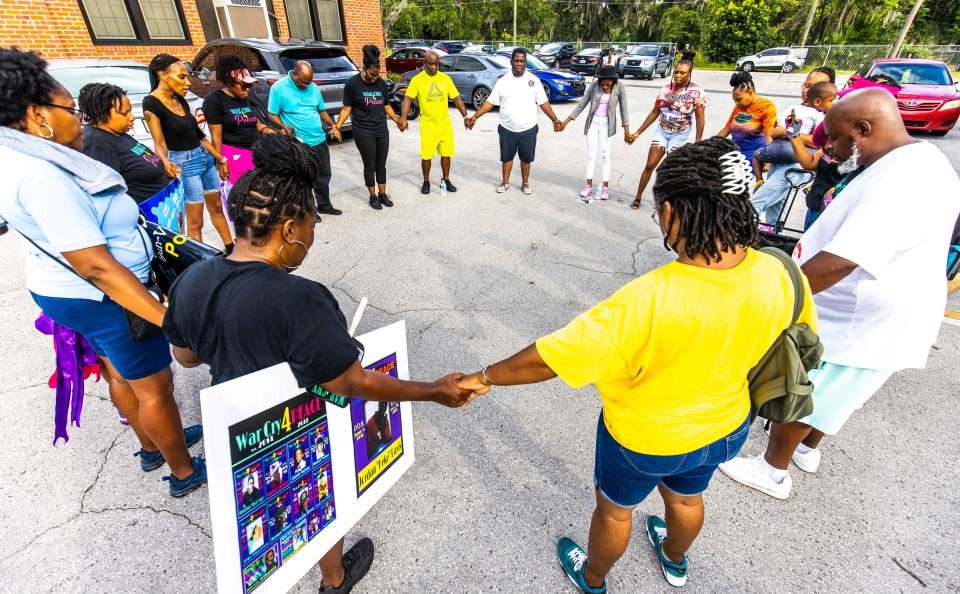 Executive Director Kimberly Wilkerson of War Cry 4 Peace, top left, leads a prayer in a prayer circle Thursday before the Prayer Walk began at Howard Academy. "We're asking God to lead us. We're asking a change in the community. We're the vessels to make the change," Wilkerson said.