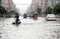 Residents travel in bicycles, tricycles and cars on a flooded street after Typhoon Usagi hit Shanwei, Guangdong province September 23, 2013. At least 25 people have been killed, including 13 in Shanwei, since typhoon Usagi made landfall in south China's Guangdong Province on Sunday evening, Xinhua News Agency reported. Picture taken September 23, 2013. REUTERS/Stringer