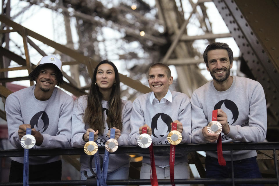 Paris 2024 Olympics Organizing Committee President Tony Estanguet, right, French athletes Marie Patouillet, center right, Sara Balzer, center left, and Arnaud Assoumani, left, present the Paris 2024 Olympic and Paralympic medals at the Eiffel Tower, in Paris, Thursday, Feb.1, 2024. (A hexagonal, polished piece of iron taken from the Eiffel Tower is being embedded in each gold, silver and bronze medal that will be hung around athletes' necks at the July 26-Aug. 11 Paris Games and Paralympics that follow. AP Photo/Thibault Camus)