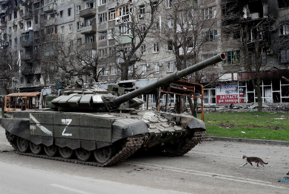 A cat walks next to a tank of pro-Russian troops in front of an apartment building damaged during Ukraine-Russia conflict in the southern port city of Mariupol, Ukraine April 19, 2022. REUTERS/Alexander Ermochenko
