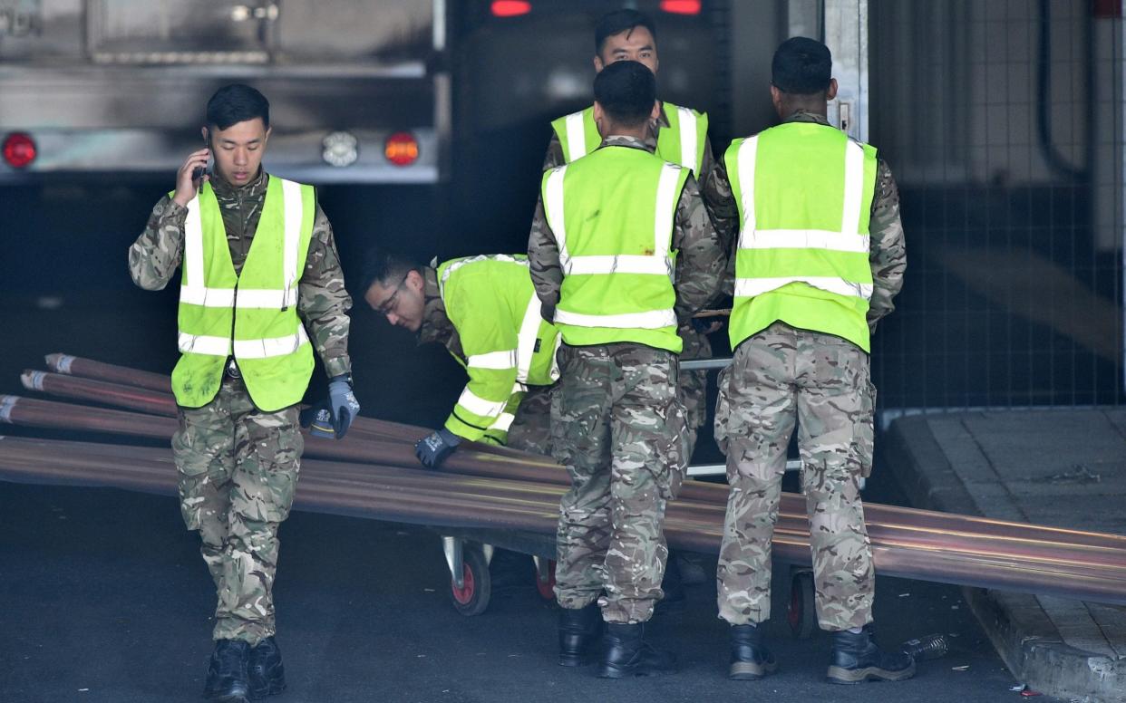 Soldiers help to unload equipment at the new NHS Nightingale hospital in London - Glyn Kirk/AFP