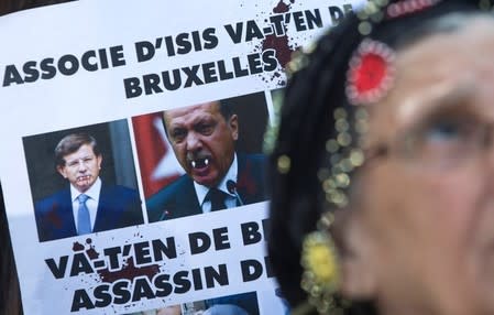 A Kurdish woman (unseen) displays a defaced picture of Turkish Prime Minister Ahmet Davutoglu and Turkish President Tayyip Erdogan during a protest outside an EU leaders summit addressing the influx of refugees and migrants flowing into Europe, in Brussels March 17, 2016. REUTERS/Yves Herman