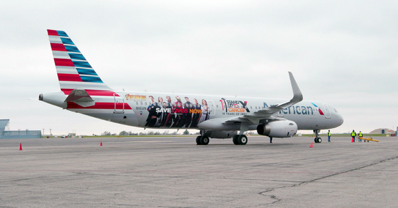 American Airlines airplane on a taxiway, with airport buildings in the distance.