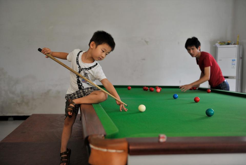 Three-year-old Wang Wuka practises snooker as his father Wang Yin positions the balls on the table at their home in Xuancheng, Anhui province, September 14, 2013. (REUTERS/Stringer)