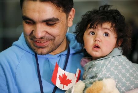 A Syrian refugee holds his daughter as they arrive at the Pearson Toronto International Airport in Mississauga, Ontario, December 18, 2015. REUTERS/Mark Blinch