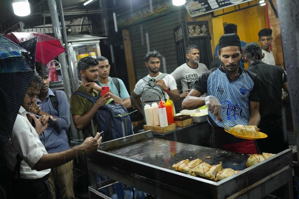 FILE - People gather around a street food vendor in Colombo, Sri Lanka, on Dec. 28, 2022. Growing numbers of people in Asia lack enough food to eat as food insecurity rises with higher prices and worsening poverty, according to a report by the Food and Agricultural Organization and other UN agencies released Tuesday, Jan. 24, 2023. (AP Photo/Eranga Jayawardena, File)