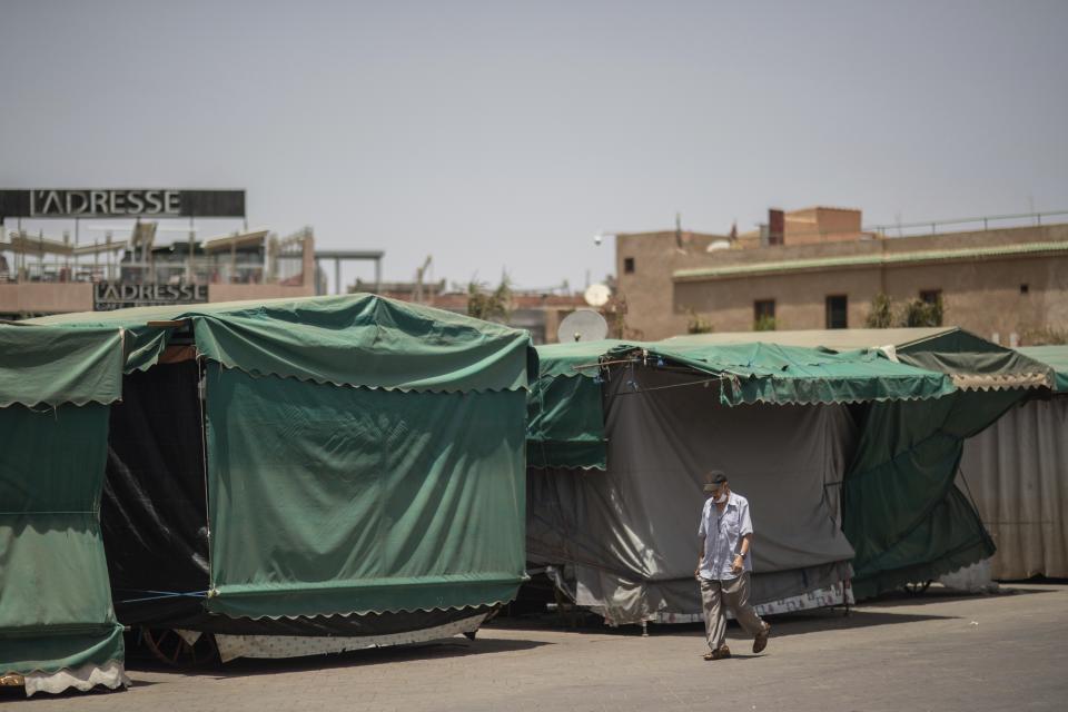 A man walks past empty stalls in the usually bustling landmark of Jemma el-Fnaa, in Marrakech, Morocco, Wednesday, July 22, 2020. (AP Photo/Mosa'ab Elshamy)