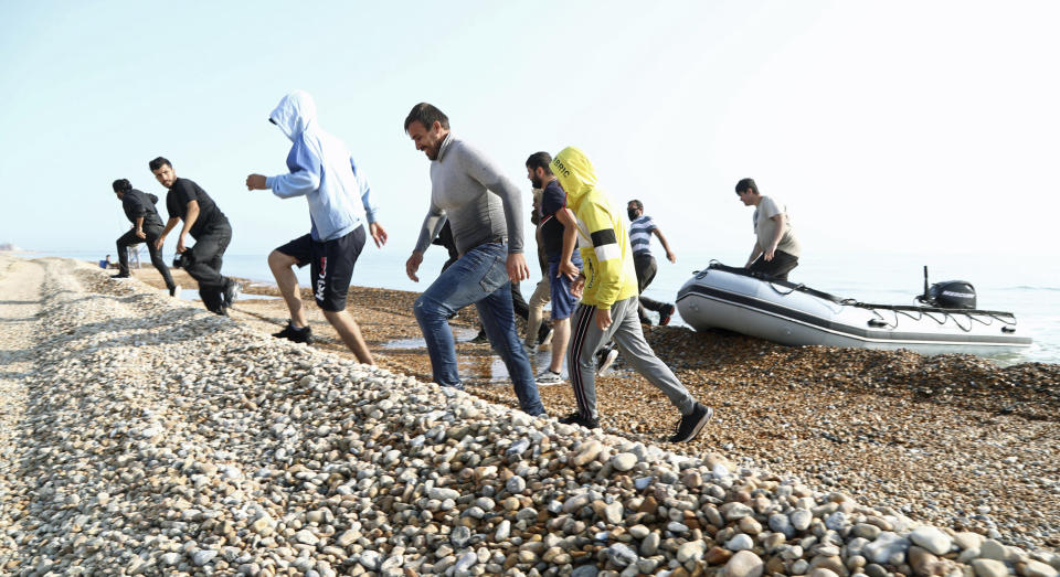 A group of people thought to be migrants run from an inflatable boat at Kingsdown beach where they arrived after crossing the English Channel, near Dover, Kent, England, Monday, Sept. 14, 2020. (Gareth Fuller/PA via AP)