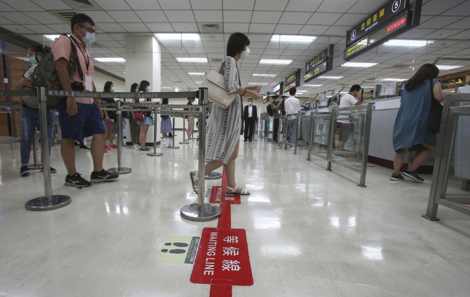 Participants line up at immigration counters for passport checks during a mock trip abroad at Taipei Songshan Airport in Taipei, Taiwan, Tuesday, July 7, 2020. Dozens of would-be travelers acted as passengers in an activity organized by Taiwan’s Civil Aviation Administration to raise awareness of procedures to follow when passing through customs and boarding their plane at Taipei International Airport. (AP Photo/Chiang Ying-ying)