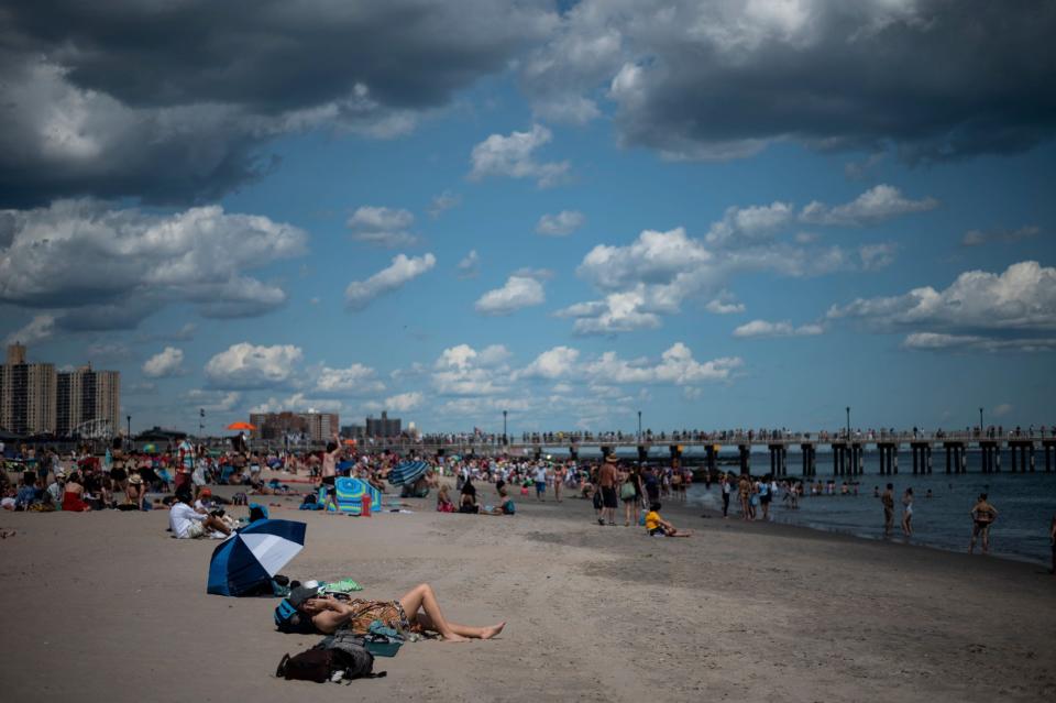 File: People enjoy the sunshine at the beach in Coney Island in New York City.