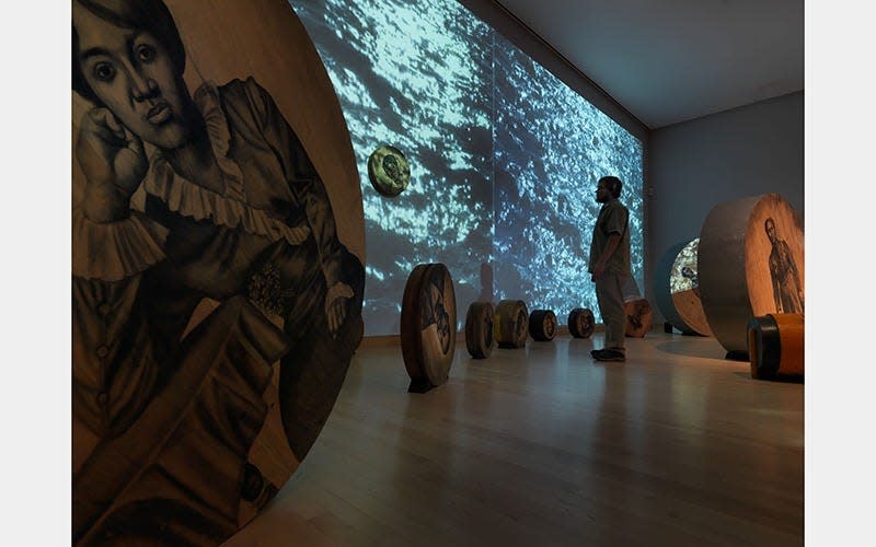 Whitfield Lovell: Passages opens at the Cincinnati Art Museum. Pictured: "Deep River" (2013), comprised of 56 wooden discs, found objects, soil, video projections and sound. Courtesy of American Federation of Arts, the artist, and DC Moore Gallery, New York.