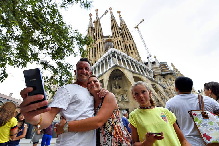 Turistas posan para una selfie frente a la Basílica de la Sagrada Familia, en Barcelona