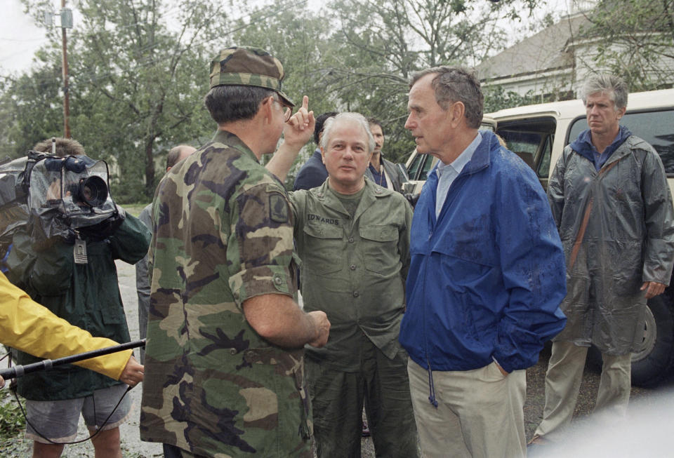 FILE - In this Aug. 26, 1992, file photo, U.S. President George H. Bush confers with Louisiana Governor Edwin Edwards, center, and a Louisiana National Guardsman in New Iberia, amid damage caused by Hurricane Andrew. Edwin Washington Edwards, the high-living four-term governor whose three-decade dominance of Louisiana politics was all but overshadowed by scandal and an eight-year federal prison stretch, died Monday, July 12, 2021 . He was 93. Edwards died of respiratory problems with family and friends by his bedside, family spokesman Leo Honeycutt said. He had suffered bouts of ill health in recent years and entered hospice care this month at his home in Gonzales, near the Louisiana capital. (AP Photo/Greg Gibson, File)