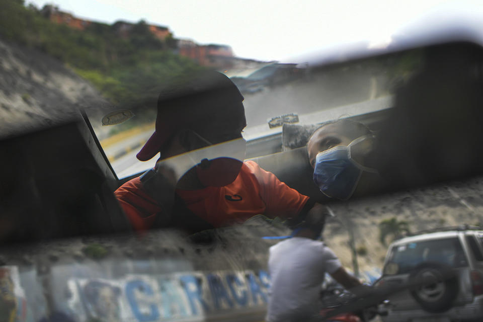 Reflected in the rearview mirror, Leo Camejo sits with his partner Ada Mendoza and their newborn baby daughter Peyton as a friend drives them home after being discharged from the hospital, in Caracas, Venezuela, Saturday, Sept. 12, 2020. The young couple met three years ago thanks to their love of soccer, as fans of the Caracas F.C. team. (AP Photo/Matias Delacroix)