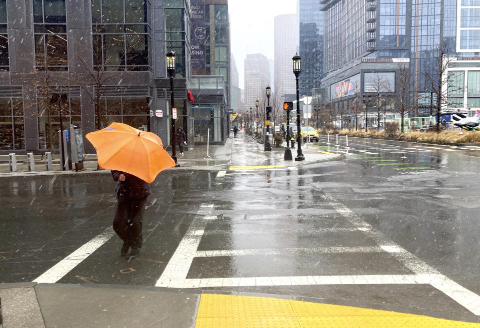 A person braces against the wind as a wintry mix of snow and rain falls in Boston, Tuesday, March 14, 2023. A winter storm is dumping heavy, wet snow in parts of the Northeast, causing tens of thousands of power outages, widespread school closings, dangerous road conditions and a plane to slide off a taxiway. The storm's path Tuesday included parts of New England, upstate New York, northeastern Pennsylvania and northern New Jersey. (AP Photo/Michael Casey)