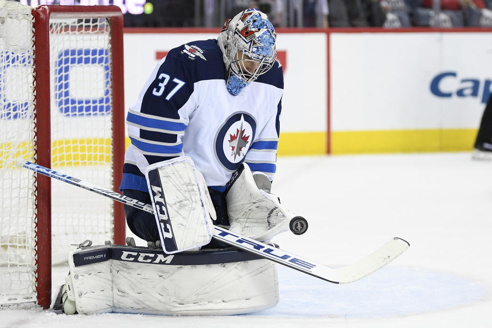 Winnipeg Jets goaltender Connor Hellebuyck (37) stops the puck during the first period of an NHL hockey game against the Washington Capitals, Sunday, March 10, 2019, in Washington. (AP Photo/Nick Wass)