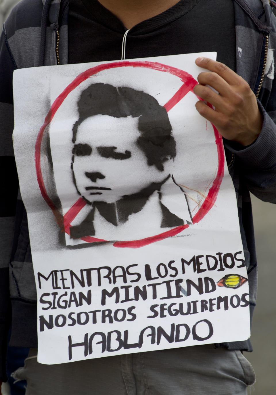 A student holds a sign during a demonstration to protest a possible return of the old ruling Institutional Revolutionary Party (PRI) and against what they perceive as a biased coverage by major Mexican TV networks directed in favor of PRI's candidate Enrique Pena Nieto in Mexico City, Wednesday, May 23, 2012. Mexico will hold presidential elections on July 1. The banner depicting Pena Nieto reads in Spanish: "While the media keeps lying, we will keep speaking." (AP Photo/Eduardo Verdugo)