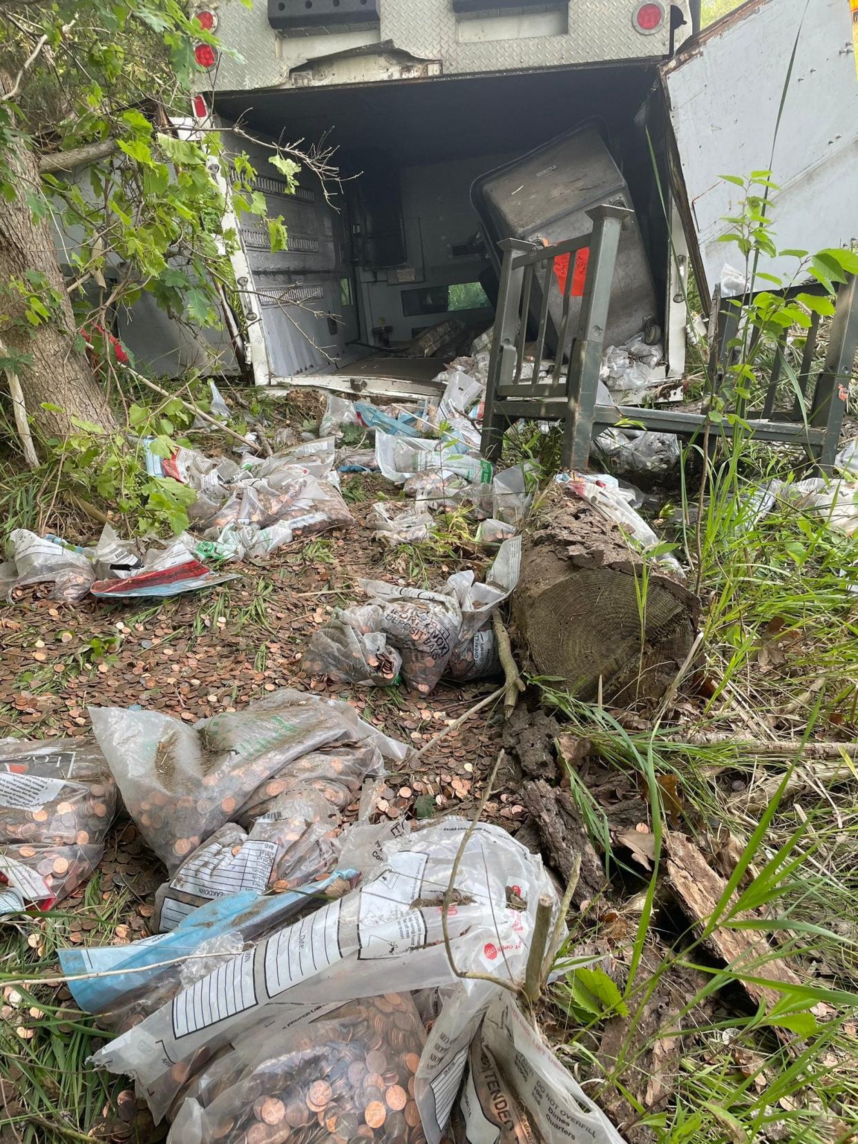 A Loomis armored truck lies on its roof with bags of coins spilled onto the ground Wednesday, July 5, 2023, south of Lansing.