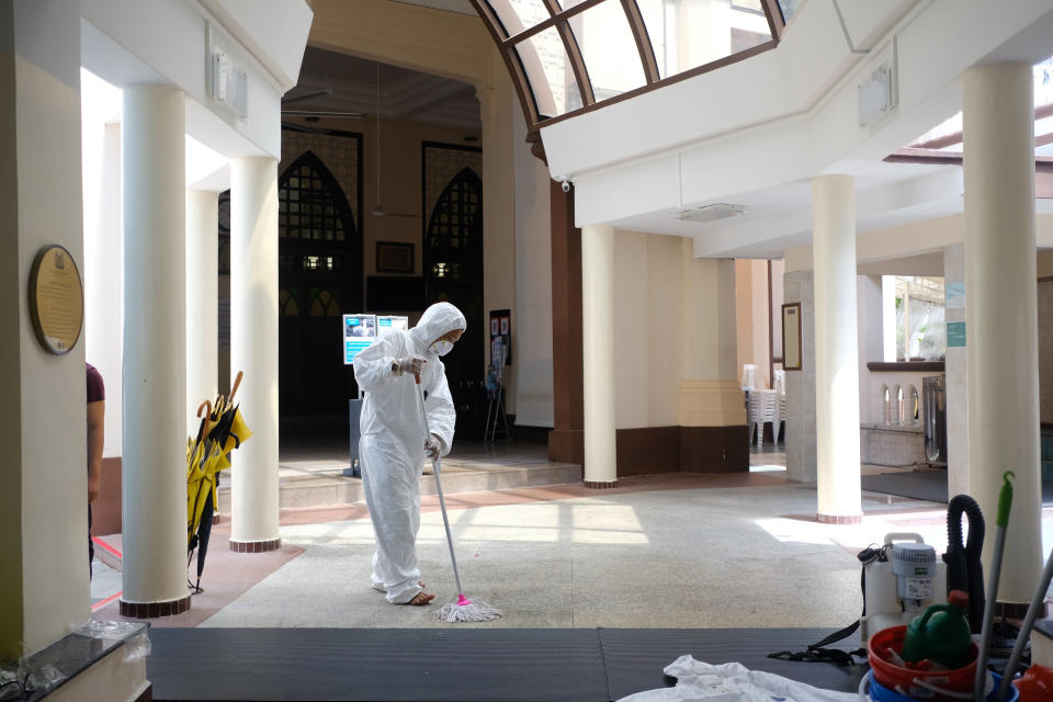 A man wearing a hazmat suit and mask mops the floor inside the Hajjah Fatimah mosque in Singapore on 13 March, 2020. (PHOTO: AP)