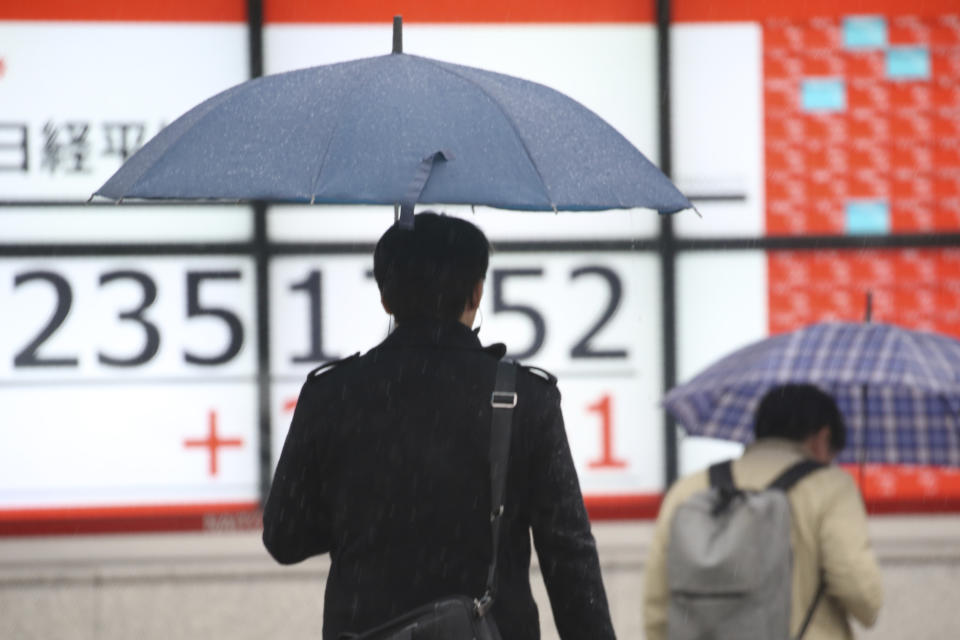 People walk by an electronic stock board of a securities firm in Tokyo, Monday, Dec. 2, 2019. Asian stock markets have risen after Chinese factory activity improved ahead of a possible U.S. tariff hike on Chinese imports. Benchmarks in Shanghai, Tokyo and Hong Kong advanced. (AP Photo/Koji Sasahara)