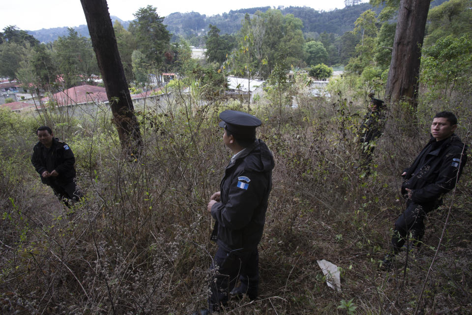 In this March 15, 2017 photo, police stand guard in the woods near the Virgen de la Asuncion Safe Home, in San Jose Pinula, Guatemala. The children's shelter, located on a hill 14 miles southeast of Guatemala City, protected by high walls and barbed wire, is surrounded by an idyllic pine forest covered with mist every morning. The forest and ravines have offered hiding places for more than 100 children who have escaped what they consider a jail. (AP Photo/Moises Castillo)