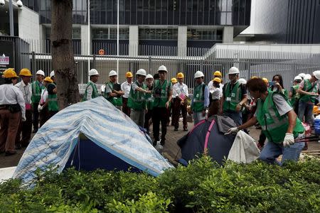 A worker from the Lands Department demolishes a tent with a cutter outside the government headquarters in Hong Kong, China June 24, 2015. REUTERS/Bobby Yip