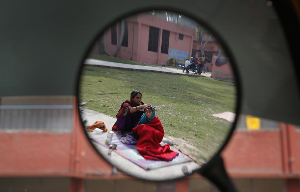 In this Monday, Feb. 3, 2014 photo, a tuberculosis patient Neha, 11, right, sits in the sun with her mother Jehana as they are reflected in the rear view mirror of a two-wheeler outside Lal Bahadur Shastri Government Hospital at Ram Nagar in Varanasi, India. India has the highest incidence of TB in the world, according to the World Health Organization's Global Tuberculosis Report 2013, with as many as 2.4 million cases. India saw the greatest increase in multidrug-resistant TB between 2011 and 2012. The disease kills about 300,000 people every year in the country. (AP Photo/Rajesh Kumar Singh)