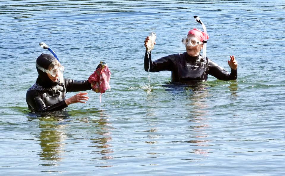 Susan Baur, left, and Mary Grauerholz surface in October 2021 with trash they collected in Deep Pond in East Falmouth. The women belong to Old Ladies Against Underwater Garbage, a group of women that retrieves trash from ponds on Cape Cod and in the region.