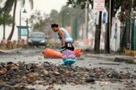 <p>A woman pulls a travel case on a rock scattered road in the aftermath of Hurricane Irma in Fajardo, Puerto Rico, on Sept. 7, 2017. (Photo: Ricardo Arduengo/AFP/Getty Images) </p>