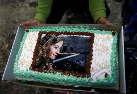 A man displays a cake with the picture of Palestinian teen Ahed Tamimi, who is detained by Israel, during a symbolic birthday party for Tamimi in the West Bank city of Hebron January 30, 2018. REUTERS/Mussa Qawasma