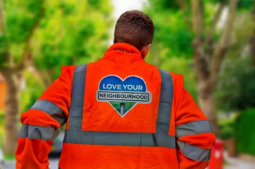 Back of a man wearing a high vis, with Love Your Neighbourhood written on it