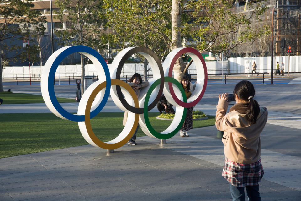 TOKYO, JAPAN - 2020/02/17: Photos of women taken posing behind the Olympic Rings near the Japan Olympic Museum and the New National Stadium in Tokyo. The stadium will serve as the main stadium for the opening and closing ceremonies and for the track and field events at the Tokyo 2020 Summer Olympic Games and Paralympic Games. (Photo by Stanislav Kogiku/SOPA Images/LightRocket via Getty Images)