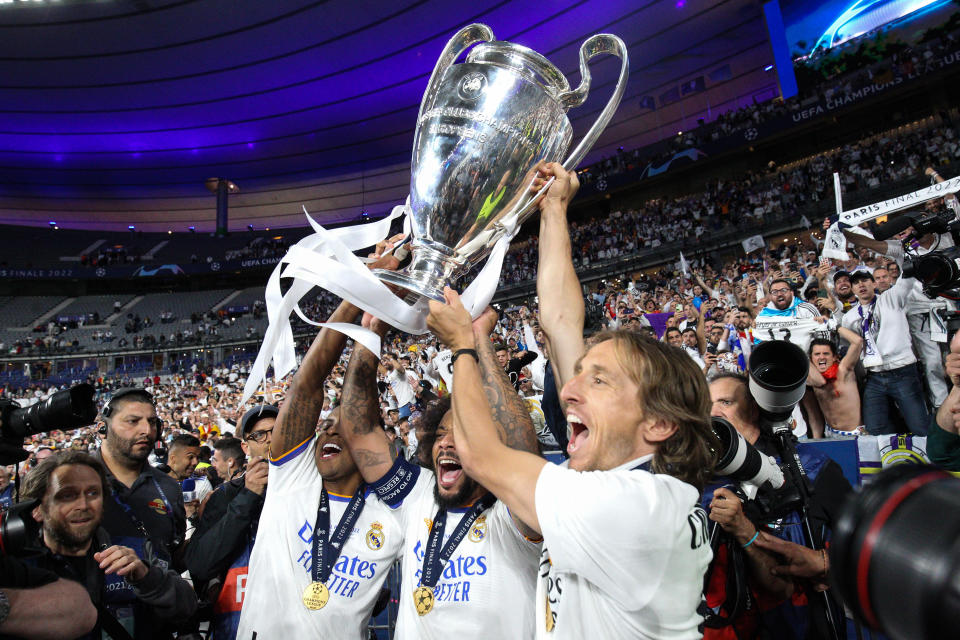 Marcelo, Rodrygo, and Luka Modric lift the UEFA Champions League trophy.