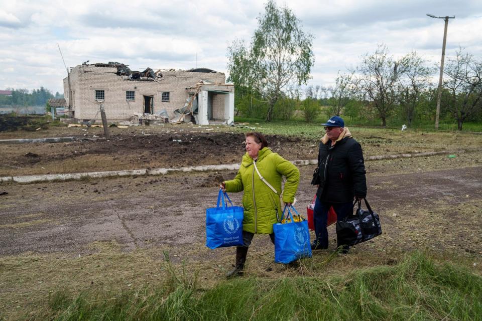 People walk with their belongings to the evacuation point in front of a building that was damaged by a Russian airstrike in Vilcha, near Vovchansk (AP)