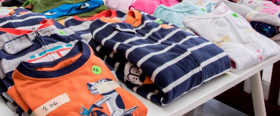 Tables of clothing and baby goods arranged at a suburban garage sale