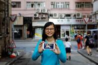 Candy Lau, who was born five months before the Hong Kong's handover to Chinese rule in 1997, poses with her childhood photo in front of the building which she being photographed in 1997, in Hong Kong, China June 6, 2017. REUTERS/Tyrone Siu