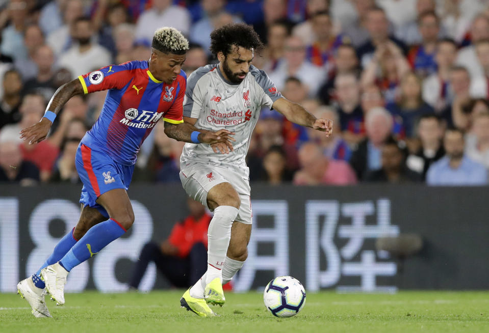 Crystal Palace's Patrick van Aanholt, left, duels for the ball with Liverpool's Mohamed Salah during the English Premier League soccer match between Crystal Palace and Liverpool at Selhurst Park stadium in London, Monday, Aug. 20, 2018. (AP Photo/Kirsty Wigglesworth)