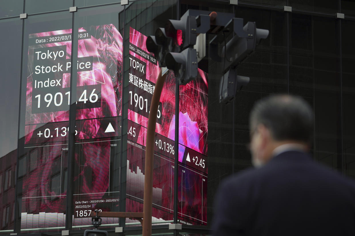 A man wearing a protective mask stands near an electronic stock board showing Japan's Tokyo Stock Price index Friday, March 18, 2022, in Tokyo. Shares were mostly lower in Asia on Friday after Wall Street extended a rally into a third day and oil prices pushed higher, surpassing $105 per barrel. (AP Photo/Eugene Hoshiko)