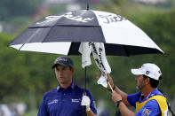 Webb Simpson keeps dry as his caddie dries off his club on the 13th green during the final round of the Sony Open PGA Tour golf event, Sunday, Jan. 12, 2020, at Waialae Country Club in Honolulu. (AP Photo/Matt York)