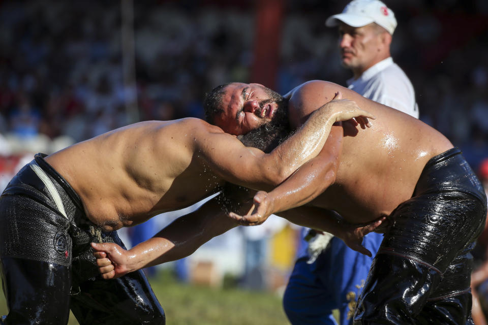 Wrestlers, doused in olive oil, compete during the 660th instalment of the annual Historic Kirkpinar Oil Wrestling championship, in Edirne, northwestern Turkey, Saturday, July 10, 2021.Thousands of Turkish wrestling fans flocked to the country's Greek border province to watch the championship of the sport that dates to the 14th century, after last year's contest was cancelled due to the coronavirus pandemic. The festival, one of the world's oldest wrestling events, was listed as an intangible cultural heritage event by UNESCO in 2010. (AP Photo/Emrah Gurel)