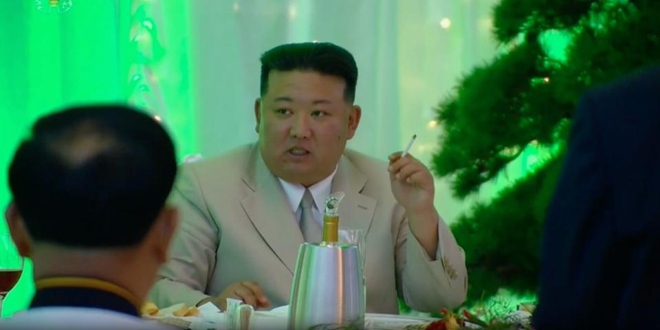 Kim Jong-Un smoking a cigarette at a banquet in Pyongyang, against a green-lit backdrop, on August 27, 2023.