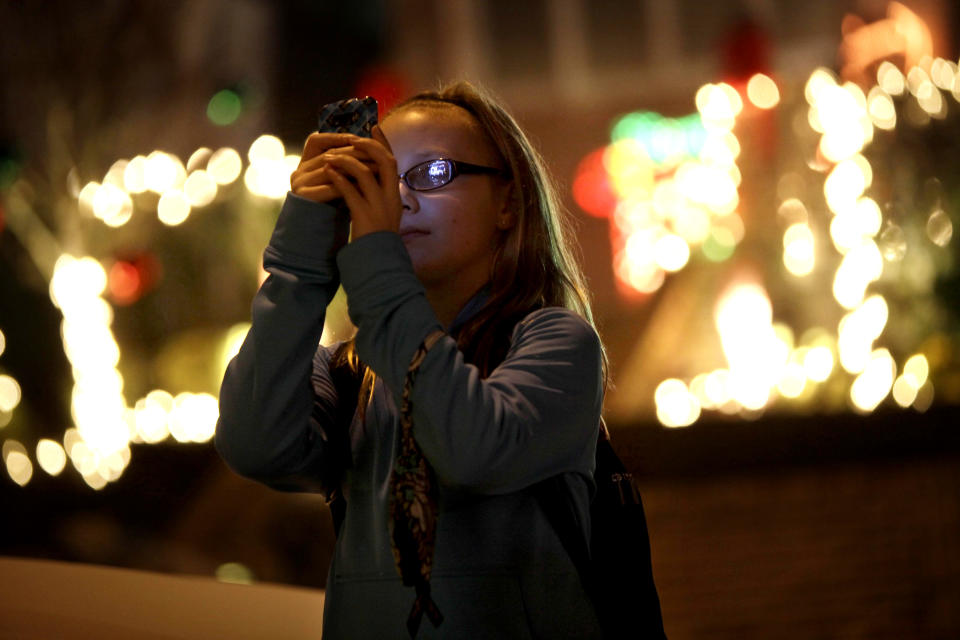 This Dec. 4, 2012 photo shows Lyvia Markle, 11, of Rochester, N.Y., taking photos of holiday displays in the Brooklyn borough of New York. Each holiday season, tour operator Muia takes tourists from around the world on his “Christmas Lights & Cannoli Tour” visiting the Brooklyn neighborhoods of Dyker Heights and Bay Ridge, where locals take pride in over-the-top holiday light displays. (AP Photo/Seth Wenig)